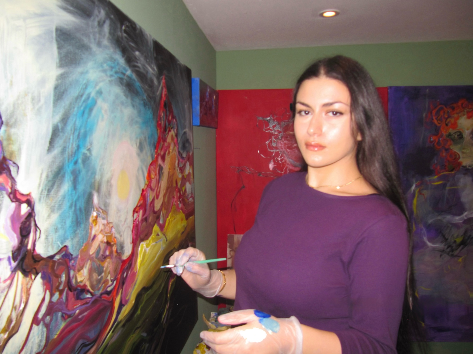 Diyara Ossi in her studio, painting on canvas