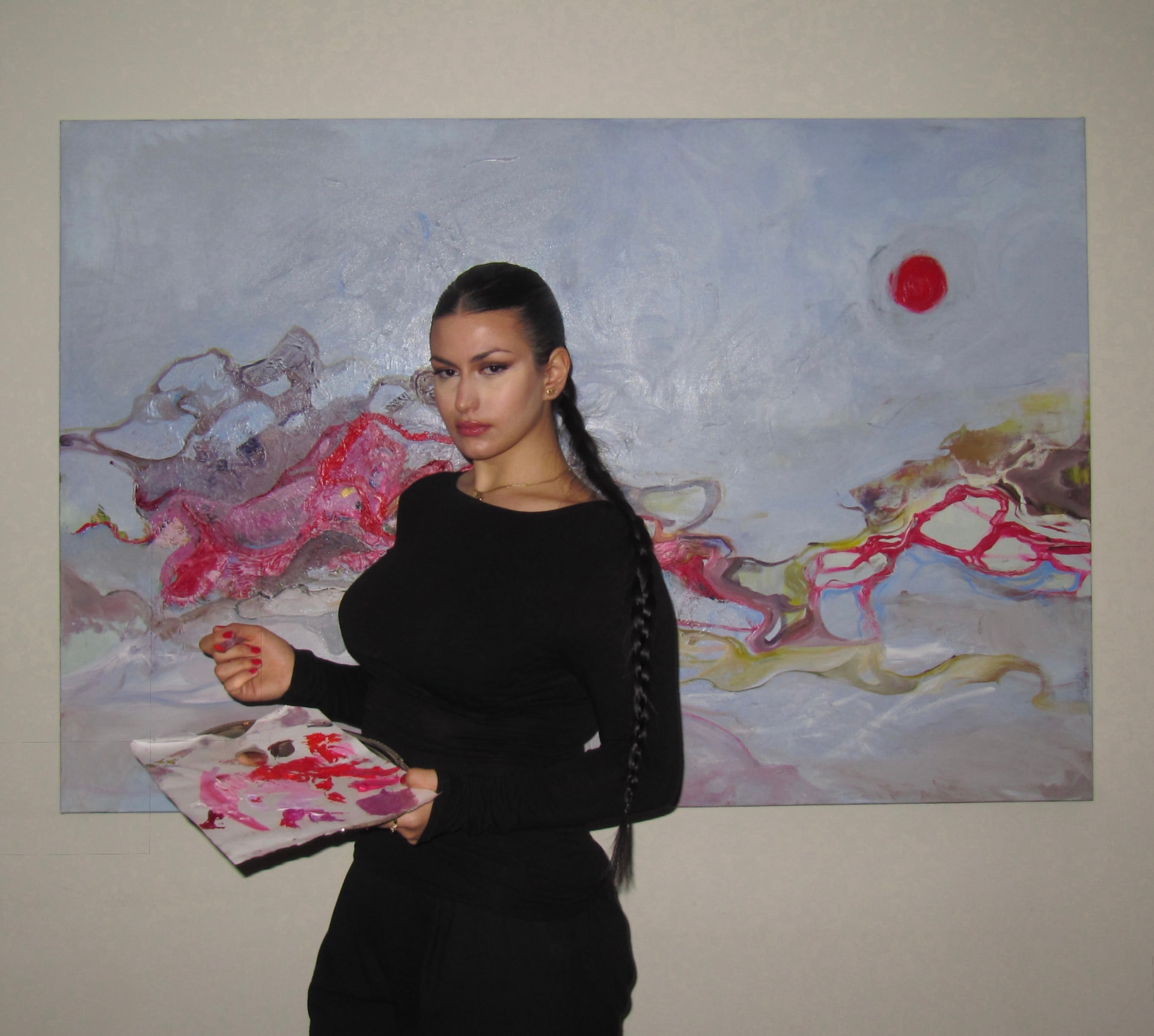 Diyara Ossi in her studio holding a palette in front of a large painting